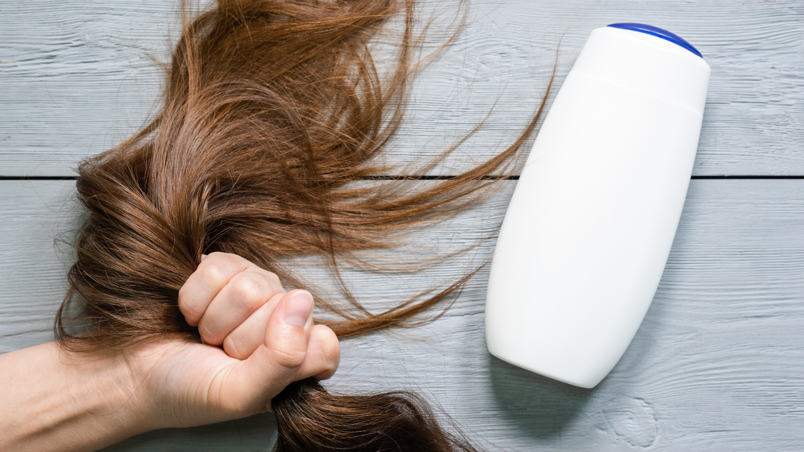 Close-up of a person tightly holding their hair, symbolizing hair fall issues, stress, or scalp concerns needing attention and care.